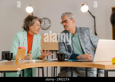 Uomo e donna d'affari senior comunicano in studio Foto Stock