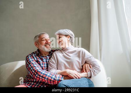 Coppia matura romantica seduta sul divano a casa Foto Stock
