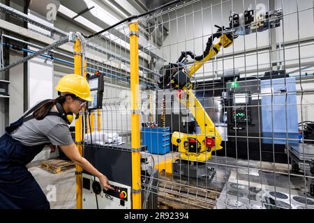 Tecnico addetto alla manutenzione che utilizza il braccio robotico in fabbrica Foto Stock