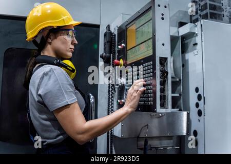 Tecnico addetto alla manutenzione che indossa la tastiera della macchina in fabbrica moderna Foto Stock