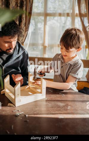 Figlio che sta imparando a costruire una casa per gli uccelli con il padre a casa Foto Stock