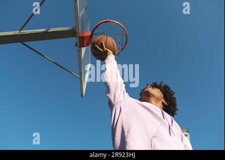 Atleta che prende il pallacanestro sotto il canestro nel campo sportivo Foto Stock