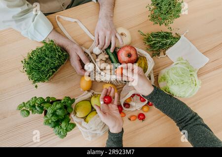 Accoppiare il disimballaggio di frutta e verdura dal sacchetto in rete Foto Stock