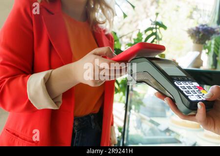 Donna che effettua pagamenti tramite smartphone al bar Foto Stock