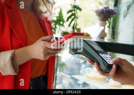 Donna che paga con il metodo "tap to pay" al bar Foto Stock