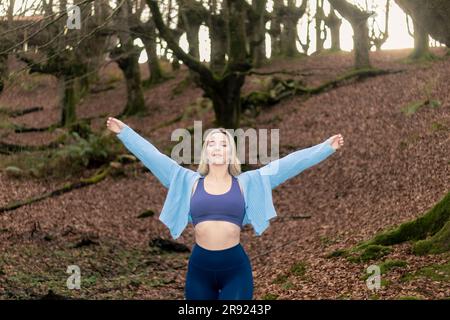 Bellezza bionda che abbraccia la serenità della natura: Respiro profondo nella foresta di faggi Foto Stock