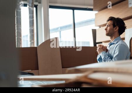 Giovane uomo d'affari premuroso seduto con le mani stringute nell'industria Foto Stock