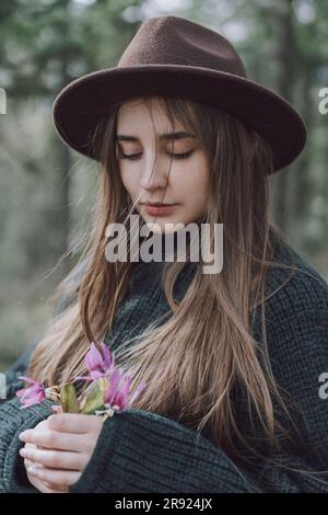 Giovane donna con capelli lunghi che regge fiori Foto Stock