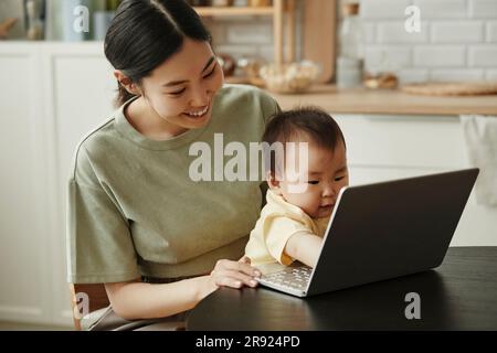Madre freelance felice con una figlia che usa il notebook a casa Foto Stock
