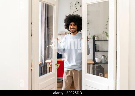 Uomo sorridente che apre le porte a casa Foto Stock