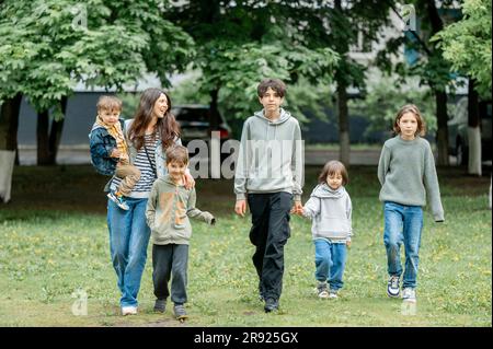 Mamma felice che cammina con i bambini nel parco Foto Stock