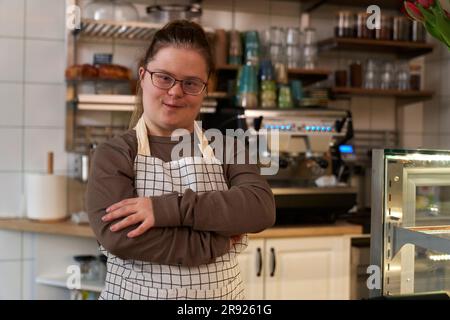 Proprietario di un caffè sorridente con sindrome di Down in piedi nel bar Foto Stock