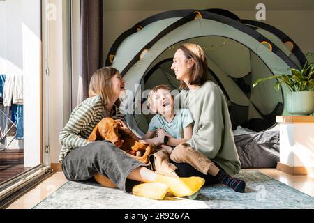 Famiglia felice con il cane Vizsla che ride e gioca a casa Foto Stock