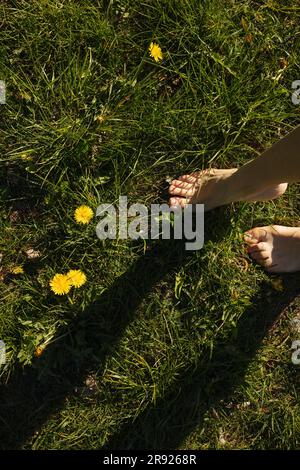 Giovane donna in piedi scalzi sull'erba Foto Stock