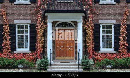 Porta d'ingresso della casa circondata dalla colorata edera in autunno Foto Stock