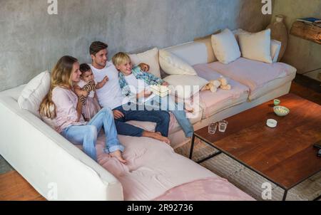 Famiglia felice che guarda la TV insieme a casa Foto Stock