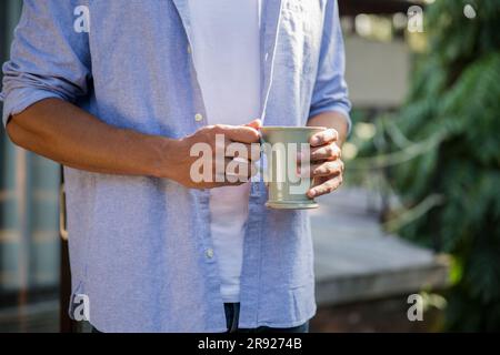 Giovane uomo in piedi con una tazza di caffè Foto Stock