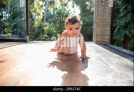 Sorridente e carina bambina che strisciava sul pavimento a casa Foto Stock