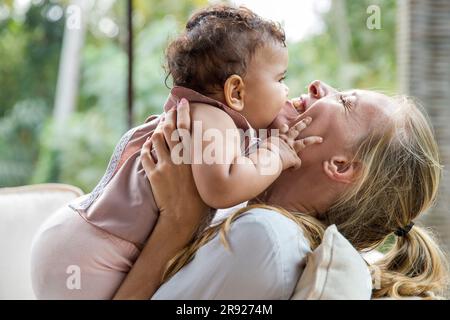 Madre allegra con una bambina che si abbraccia a casa Foto Stock