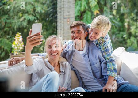 Donna felice che fa selfie con la famiglia a casa Foto Stock