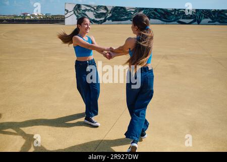 Ragazze felici che si tengono per mano e giocano nelle giornate di sole Foto Stock