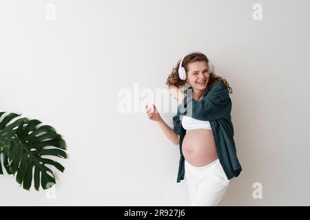 Felice donna incinta che si diverte ad ascoltare la musica Foto Stock