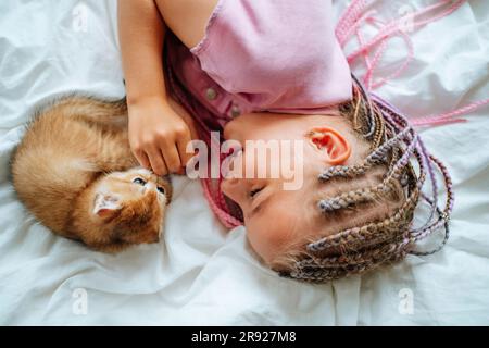 Ragazza sorridente che gioca con gatto sul letto Foto Stock