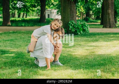 Madre che sostiene la figlia e si accovaglia nel parco Foto Stock