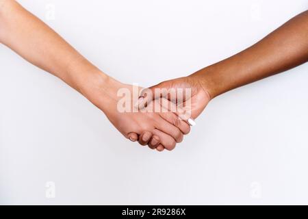 Immagine ritagliata di amici che si tengono per mano su sfondo bianco Foto Stock