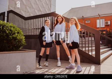 Sorridenti ragazze scolastiche in piedi vicino alle scale sul cortile della scuola Foto Stock