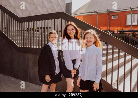 Sorridenti amici di scuola in piedi vicino alle scale sul cortile della scuola Foto Stock