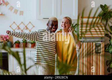 Giocosa e sorridente coppia che si muove in cucina Foto Stock