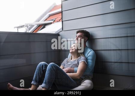 Felice giovane coppia seduto sul balcone Foto Stock