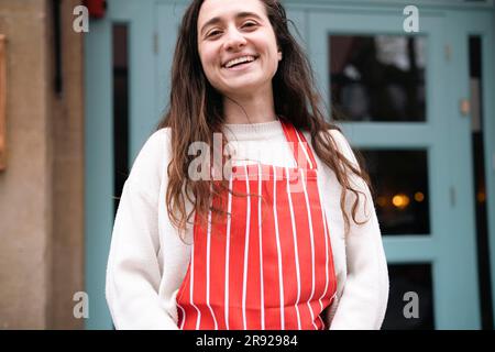 Fiorista felice che indossa grembiule davanti al negozio Foto Stock