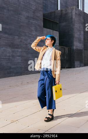 Donna d'affari che nasconde la faccia dal sole vicino all'edificio Foto Stock