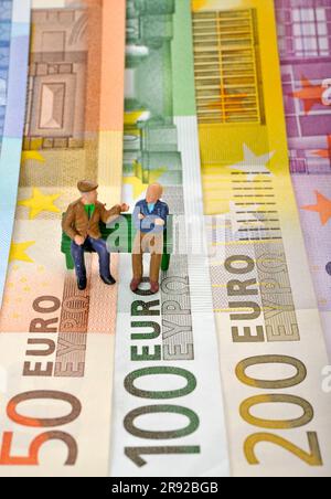 cifre sulle banconote in euro, due pensionati seduti su una panchina Foto Stock