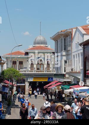 Turisti nella città di Adalar sull'isola di Büyükada, Isole Principesse, Mare di Marmara, vicino a Istanbul, Turchia. Edificio dei traghetti con tetto a cupola dietro. Foto Stock