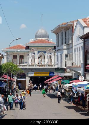 Turisti nella città di Adalar sull'isola di Büyükada, Isole Principesse, Mare di Marmara, vicino a Istanbul, Turchia. Edificio dei traghetti con tetto a cupola dietro. Foto Stock