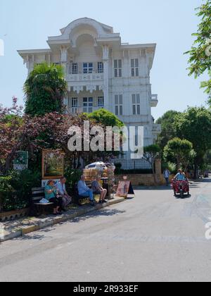 La gente siede all'ombra di fronte a una villa in legno dell'epoca ottomana. Adalar sull'isola di Büyükada, Isole Principesse, Mare di Marmara, vicino a Istanbul, Turchia Foto Stock