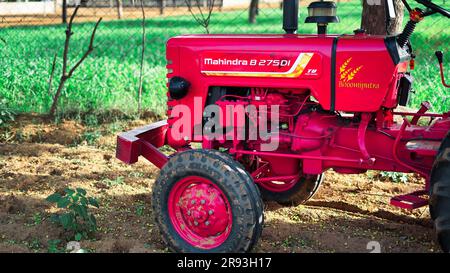 Agricoltore nel trattore che prepara terreni agricoli con letto di semina per il raccolto successivo. Dettagli del moderno trattore rosso primo piano, vista laterale, pneumatici neri Foto Stock