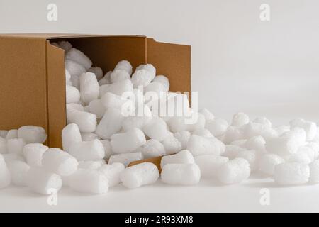 Scatola di cartone isolata sullo sfondo bianco riempita con arachidi di imballaggio Foto Stock