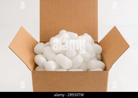 Scatola di cartone isolata sullo sfondo bianco riempita con arachidi di imballaggio Foto Stock