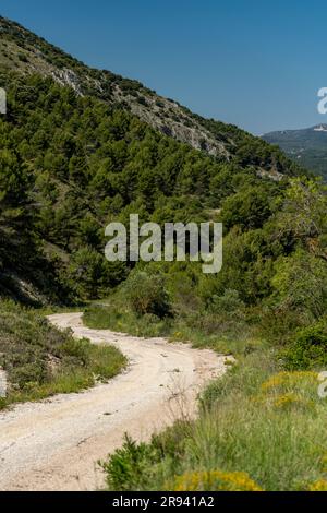 Piccola strada di montagna ghiaiosa che passa sopra una catena montuosa, Costa Blanca, Alicante, Spagna Foto Stock