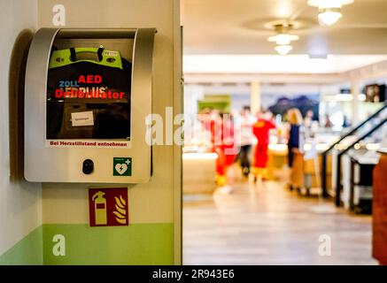 PRODUZIONE - 08 giugno 2023, Schleswig-Holstein, umido: Un defibrillatore si trova all'ingresso di un ristorante in un complesso di appartamenti umidi. Gli anni '1960 e '1970 videro la creazione delle strutture di base per il turismo moderno nello Schleswig-Holstein. Dove oggi le famiglie giocano a minigolf, i marinai saltellano nel porto e le coppie godono di un trattamento benessere, è stato poco più di 50 anni fa: Praticamente nulla. Ma le cose cambiarono presto. Nel mezzo di campi, prati e del Mar Baltico, un centro vacanze con il nome futuristico "Dump 2000" è stato costruito dal 1969 al 1973 nella comunità di Dump, un'ex tenuta. Foto Stock