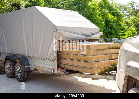 Trasporto di pannelli isolati per facciate in un rimorchio per auto. rimorchio carico. Foto Stock