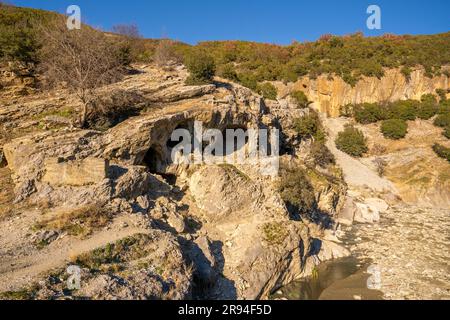 Alti canyon con vegetazione verde lungo il fiume Osumi in Albania. Una stretta valle e un piccolo ponte che collega i canyon. Foto Stock