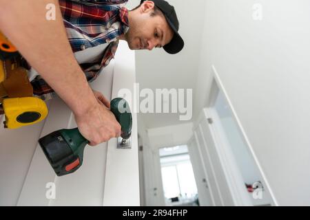 Installazione con una serratura nel battente della porta utilizzando un trapano avvitatore Foto Stock