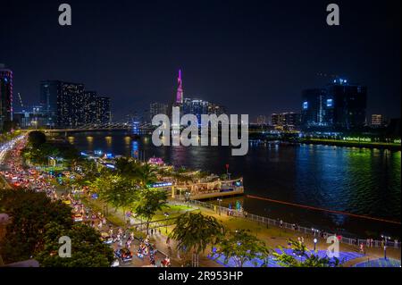 Vista notturna del fiume Saigon, del ponte Ba Son e dell'edificio Vinpearl Landmark 81 parzialmente coperto dalla torre del ponte nella città di ho chi Minh, Vietnam. Foto Stock