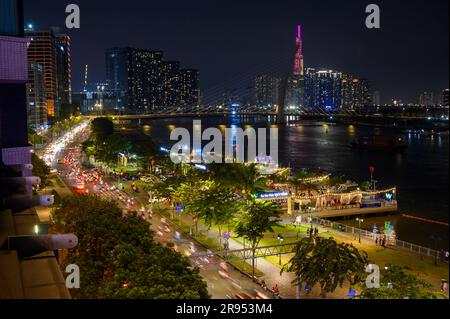 Vista notturna del fiume Saigon, del ponte Ba Son e dell'edificio Vinpearl Landmark 81 parzialmente coperto dalla torre del ponte nella città di ho chi Minh, Vietnam. Foto Stock