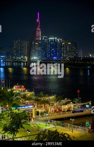 Vista notturna del fiume Saigon, del ponte Ba Son e dell'edificio Vinpearl Landmark 81 parzialmente coperto dalla torre del ponte nella città di ho chi Minh, Vietnam. Foto Stock